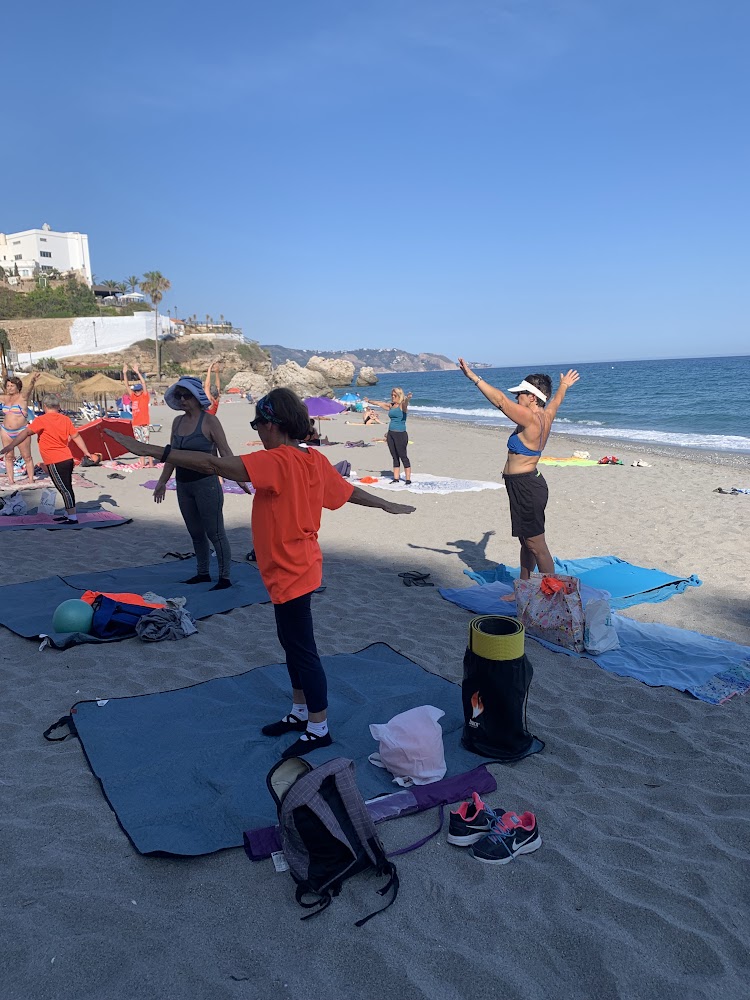 Morgentræning på stranden El Salón i Nerja med måtter i sandet og havet i baggrunden